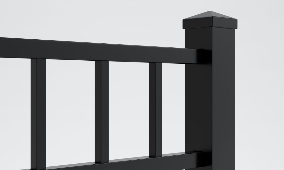 Close-up view of a black metal fence with vertical posts and horizontal rails. The background is plain and light-colored, and one fence post is topped with a flat cap.