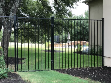 backyard protected by tall steel picket fence with gate