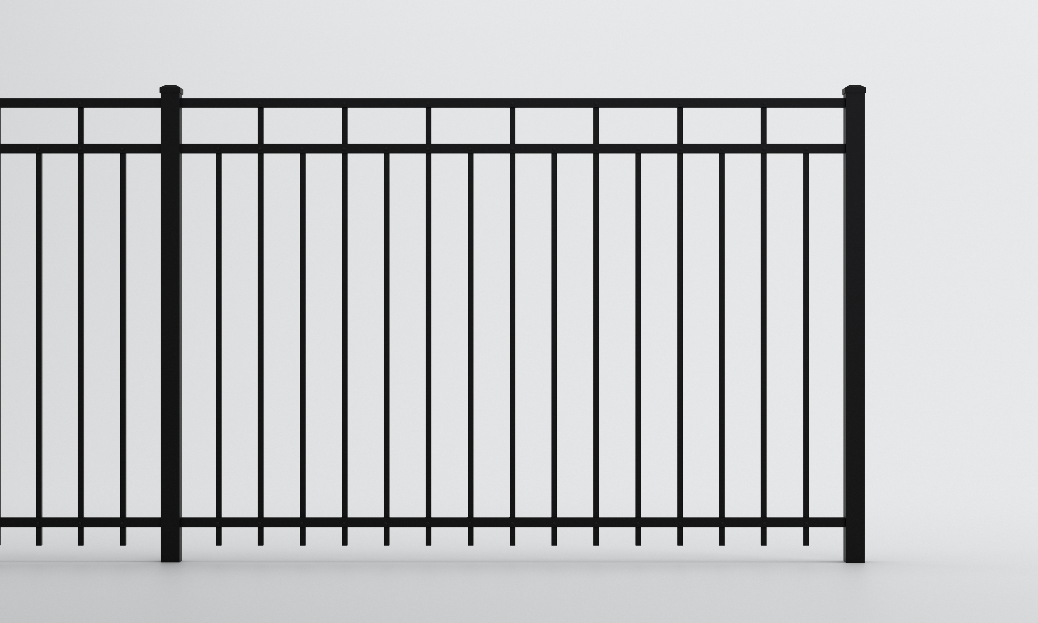 A black metal fence with vertical bars and a horizontal top rail stands against a plain white background.