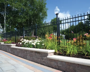 black aluminum picket fence along page and flower bed