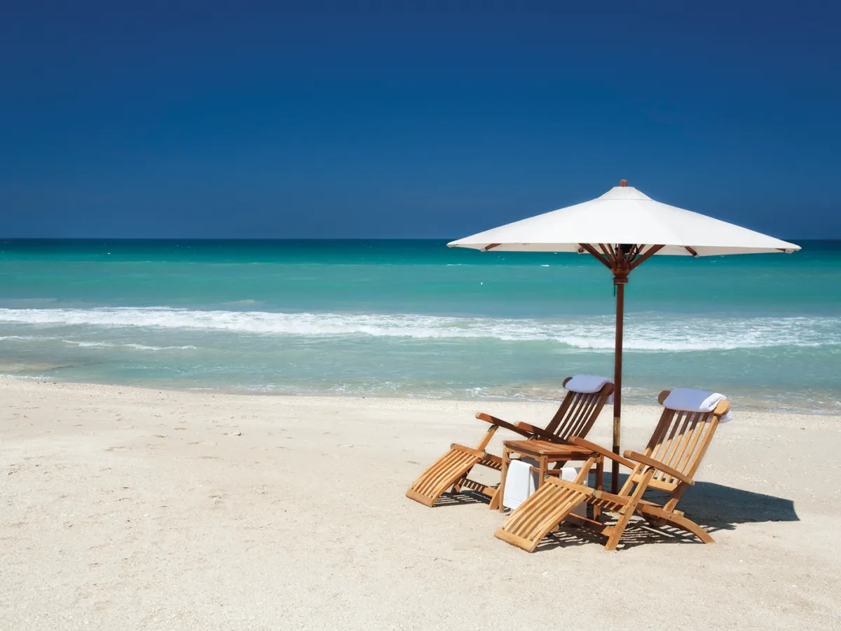 lounge chairs under umbrella on the beach